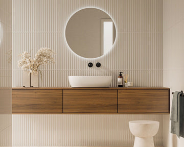 Modern bathroom with wooden vanity, round mirror, and white toilet.
