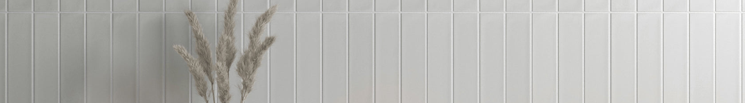 Decorative vase with dried plants on a white tiled wall
